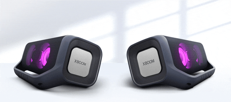 Na bielom pozadí sú zobrazené dva reproduktory LG XBOOM Go smerujúce od seba. Oba majú purpurové osvetlenie.