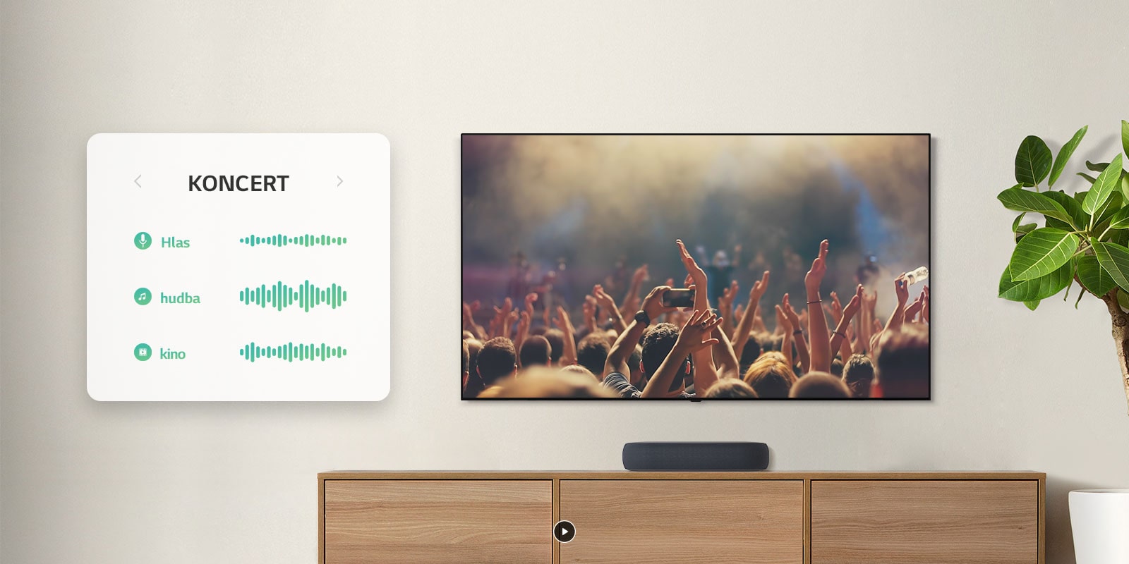 TV je umiestnený na stene. Na obrazovke sú tlieskajúci ľudia na koncerte. Kanál sa prepne na filmovú scénu, kde auto jazdí lesom. Kanál sa znova prepne na správy, kde vystupuje hlásateľ. Sound Bar LG sa nachádza priamo pod TV na drevenej poličke.