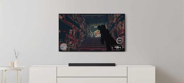 TV a Soundbar v obývačke. Na TV obrazovke je akčná hra a TV kanál je prepnutý na futbalový zápas. (prehrať video)