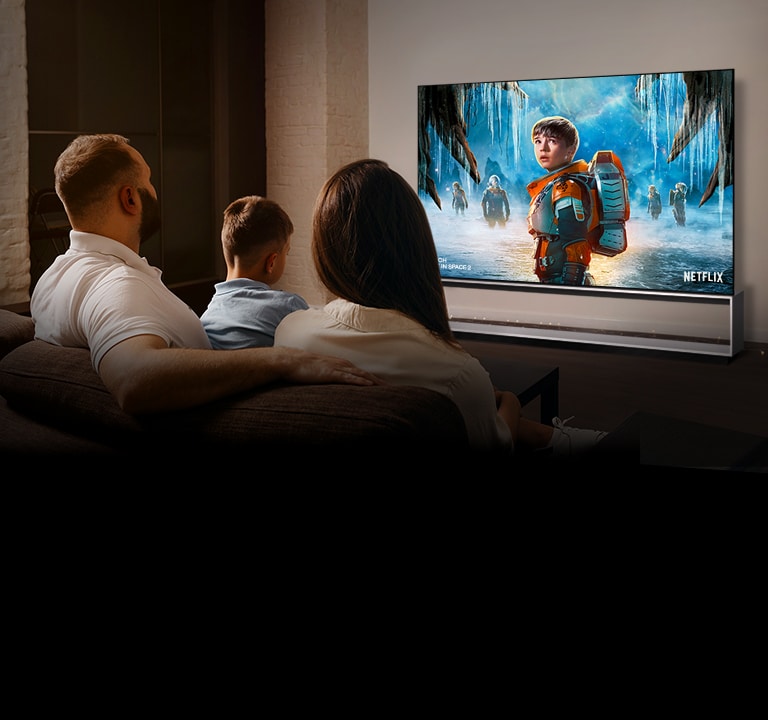 Pár sediaci na pohovke v obývačke a sledujúci seriál LOST IN SPACE 2 v televízii