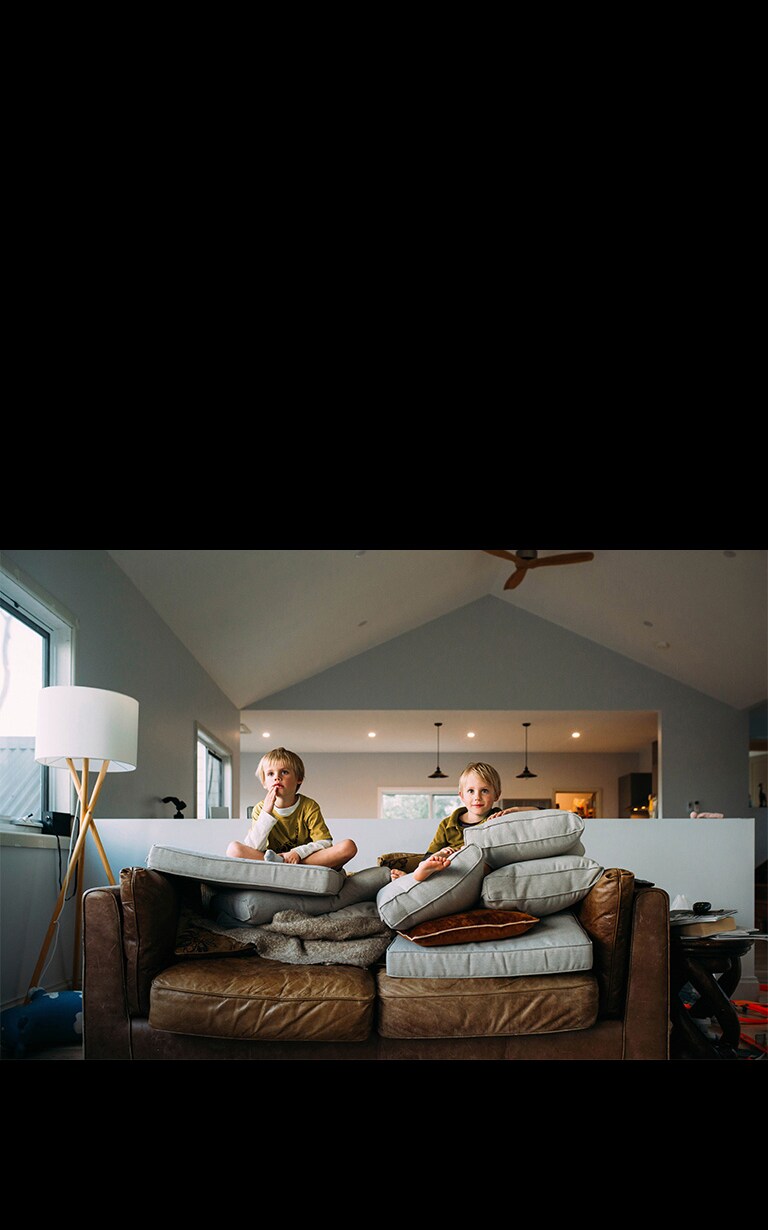 Dve dvojčatá sedia na pohovke a niečo sledujú.