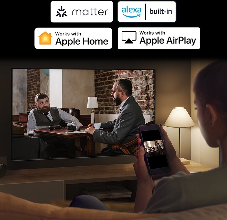 Žena v tmavej miestnosti sleduje video z telefónu na obrazovke televízora prostredníctvom zrkadlenia.