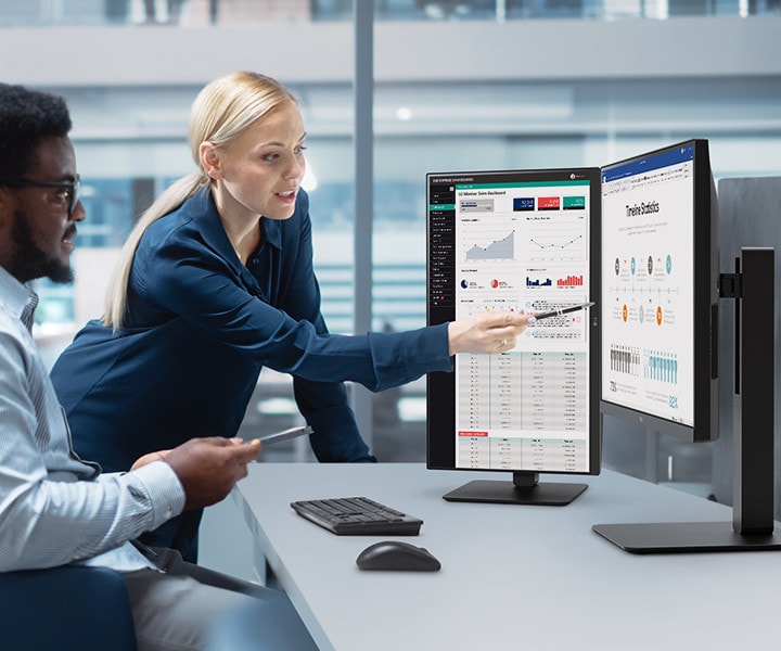 Dvaja zamestnanci, muž a žena, diskutujú pri pohľade na monitor v kancelárii.