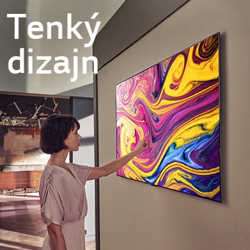 Žena sa pozerá na televízor osadený na stene, na ktorom je zobrazené umelecké dielo.