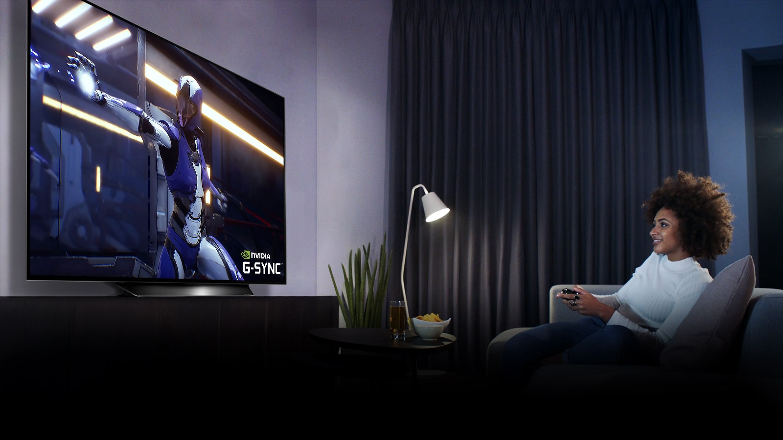 Žena sediaca na pohovke, drží joystick pri hraní hier na televíznej obrazovke