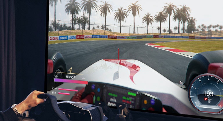 Pohľad zblízka na hráča, ktorý drží herný volant a hrá závodnú hru na televízore.