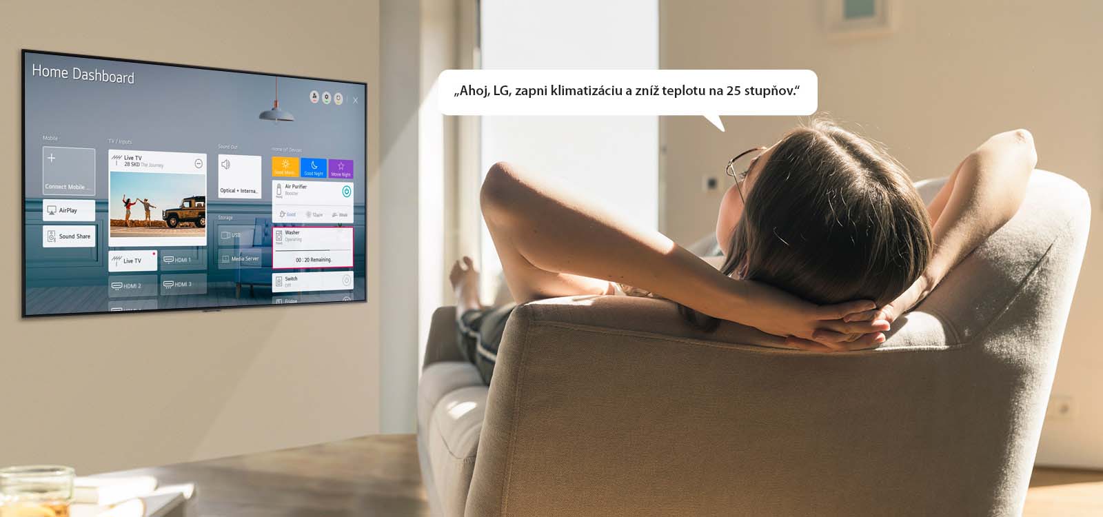 Žena ležiaca na gauči hovorí televízoru, aby znížil teplotu, pričom na obrazovke televízora je zobrazený hlavný panel