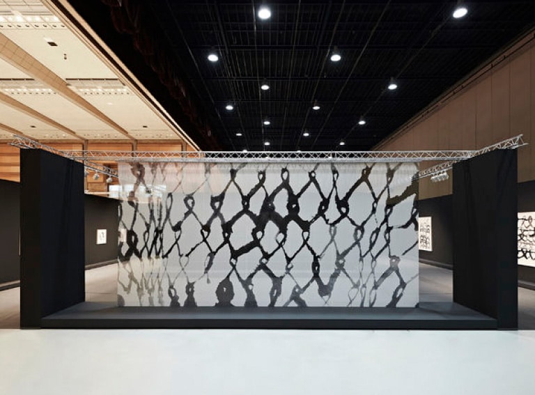 Œuvre d’art représentée sur un panneau transparent dans une salle d’exposition. 