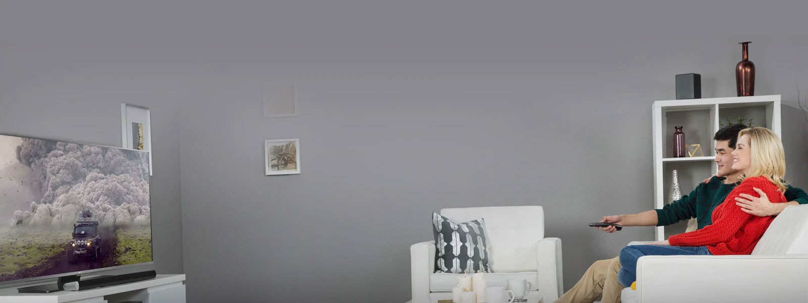 Téléviseur LG de côté affichant un film tandis qu’un couple regarde l’écran depuis un canapé placé en face du téléviseur