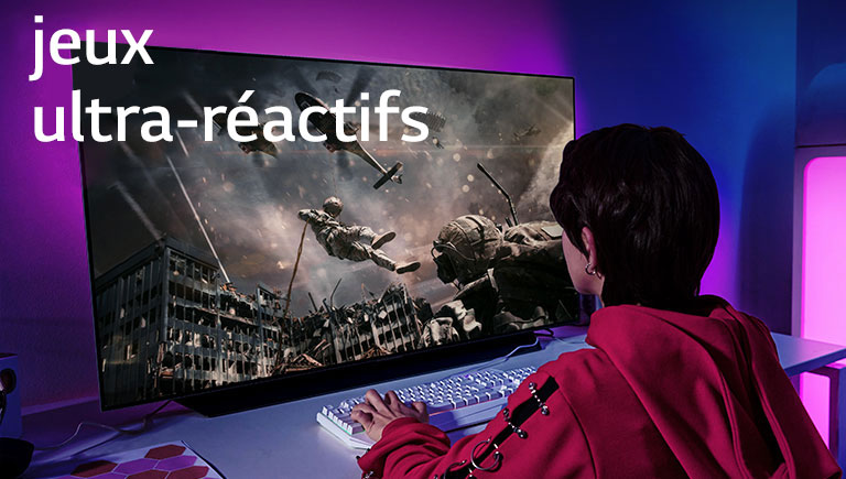 Une fille jouant à un jeu d’ordinateur avec un téléviseur grand écran affichant un soldat descendant d’un hélicoptère.