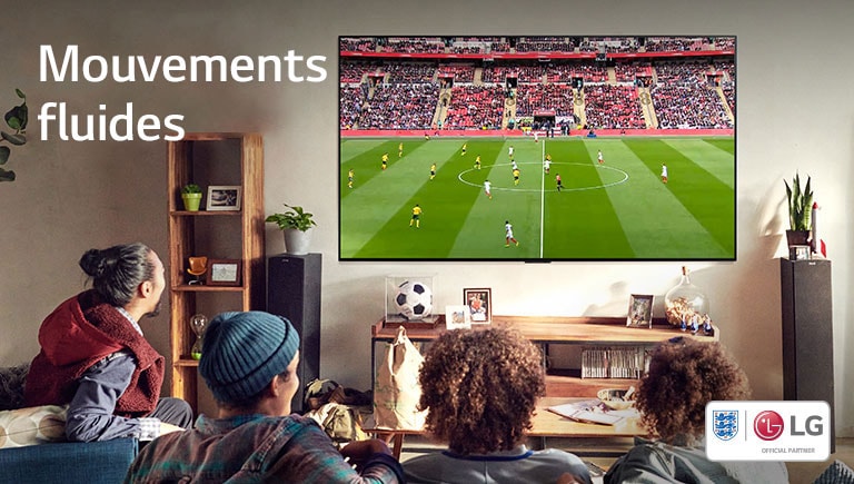 Quatre personnes assises sur un canapé regardent un match de football dans un salon.