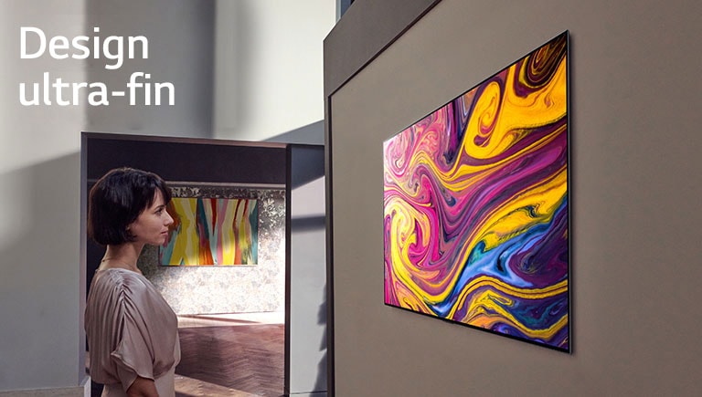 Une femme regarde un téléviseur fixé sur le mur qui affiche une œuvre d’art.