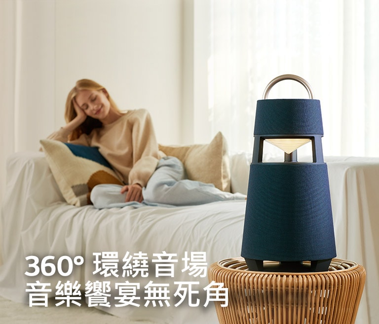 一位女性坐在沙發上享受LG XBOOM 360ﾟ 環繞音場體驗的圖片。