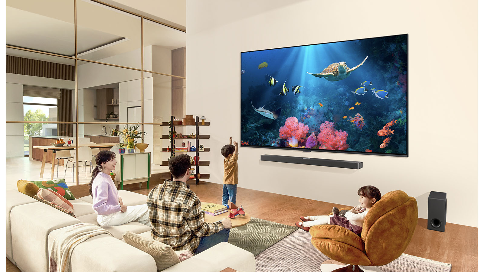一家人在客廳中觀看壁掛的超大型 LG TV，螢幕上顯示包括珊瑚和海龜的海洋景色。