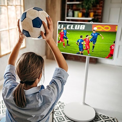 在 StanbyME 上觀看足球比賽。顯示一名女子把一顆足球舉過頭頂的背影。