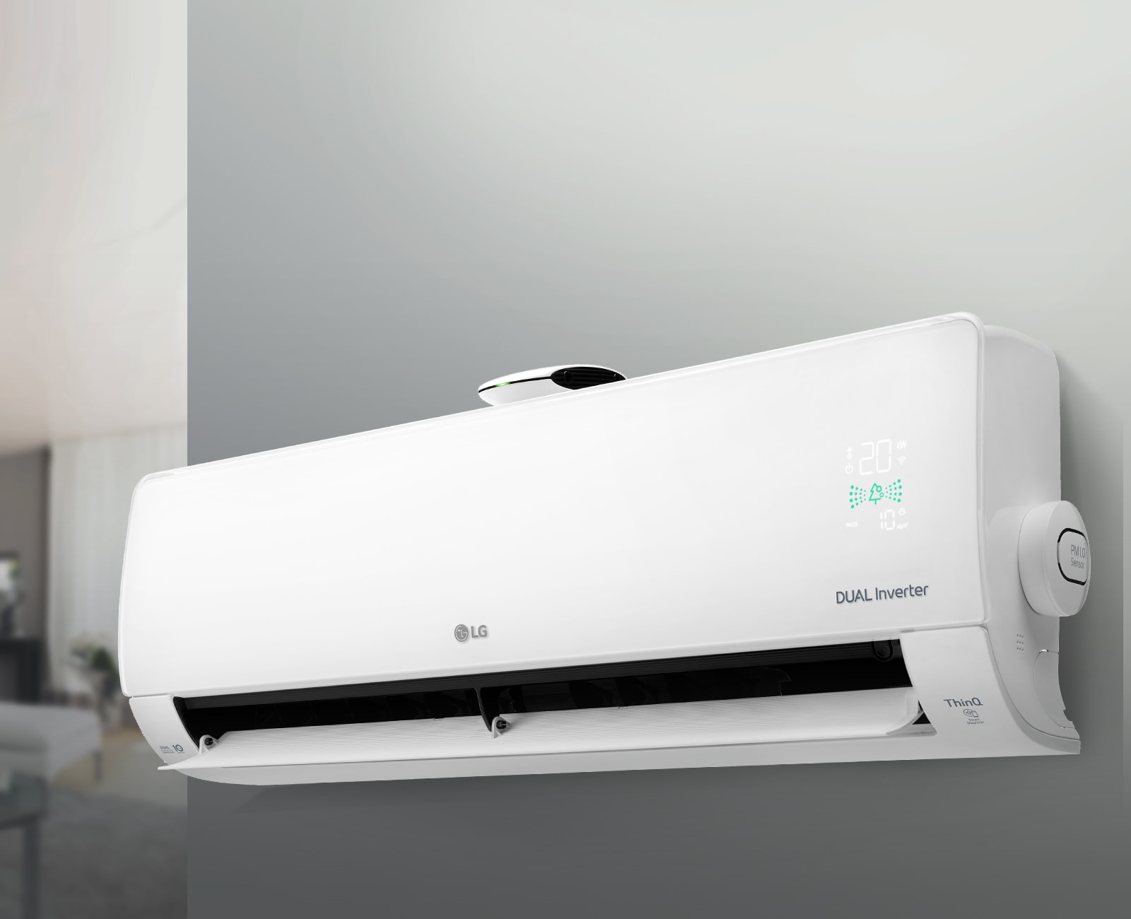 Білий кондиціонер висить на сірій стіні, жалюзі відкриті. Позаду ліворуч видніється розмитий інтер'єр кімнати.