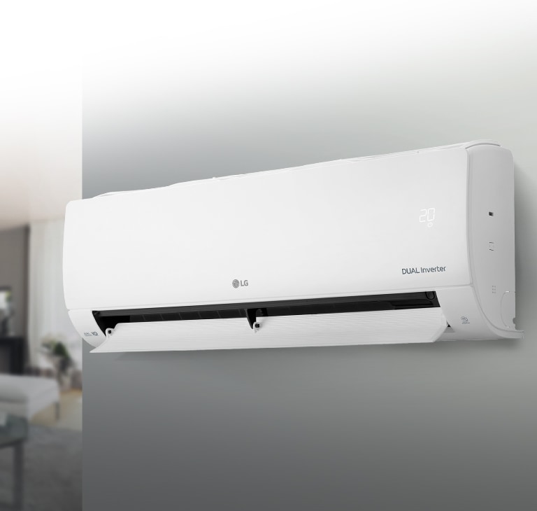 Білий кондиціонер висить на сірій стіні, жалюзі відкриті. Позаду ліворуч видніється розмитий інтер'єр кімнати.