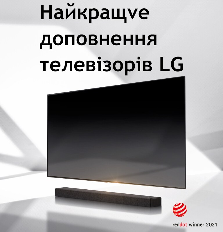Саундбар і телевізор розташовано на підлозі білого кольору, а ззовні праворуч падає тінь.