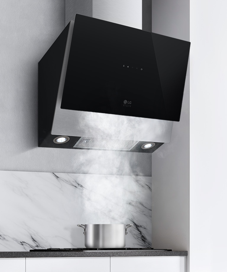 The black hood is shown with lights on the underside on above a steaming pot on the stove.