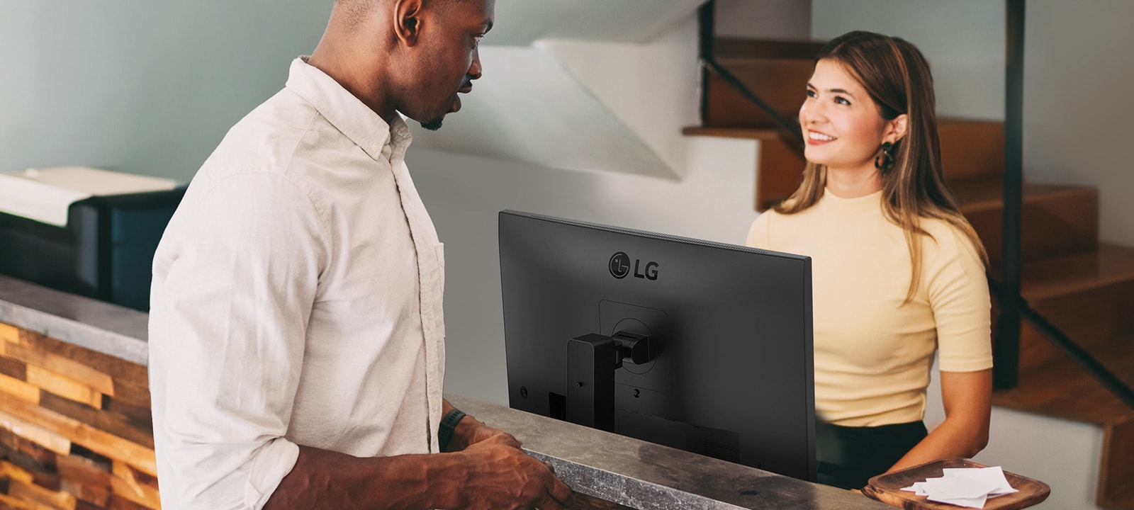 Жінка-адміністратор розмовляє з чоловіком на стійці реєстрації.