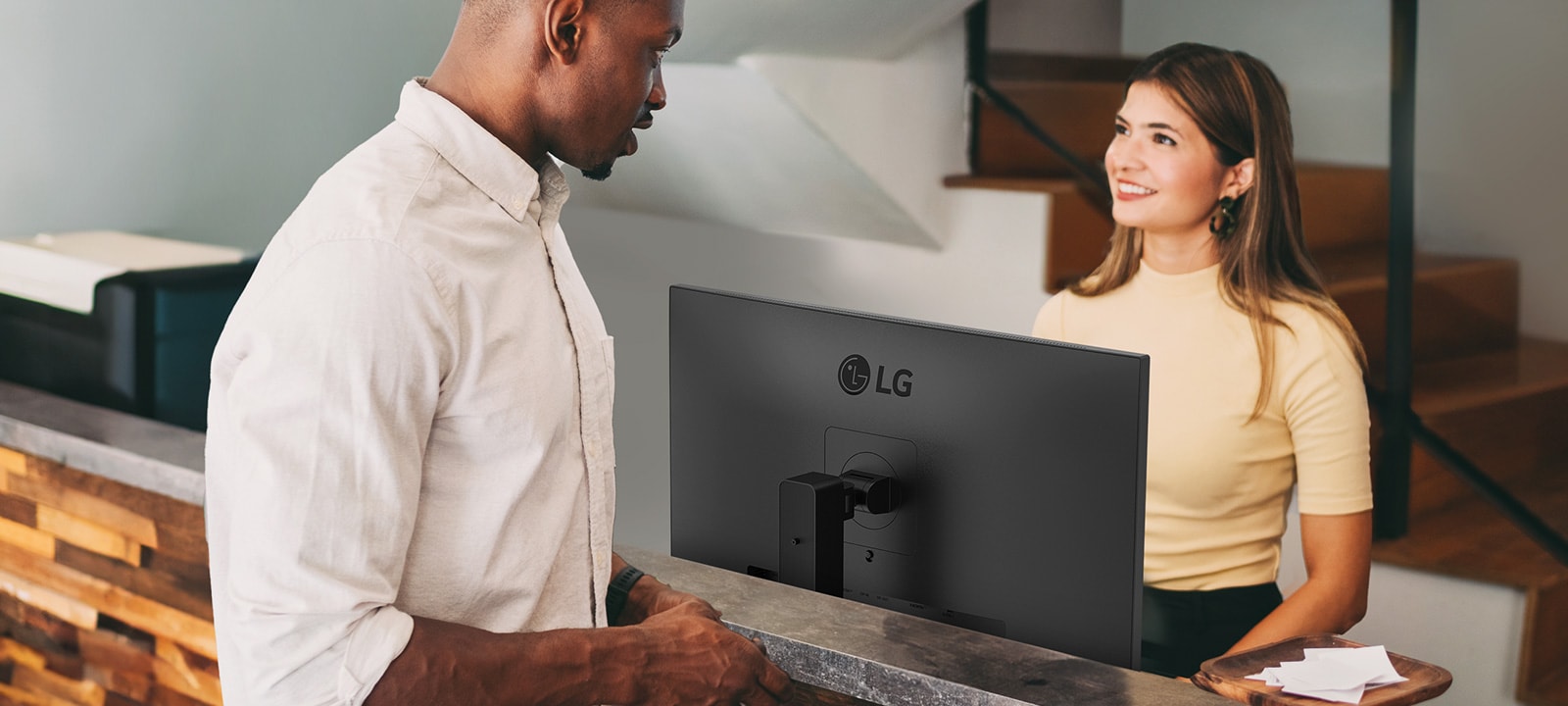 Жінка-адміністратор розмовляє з чоловіком на стійці реєстрації.