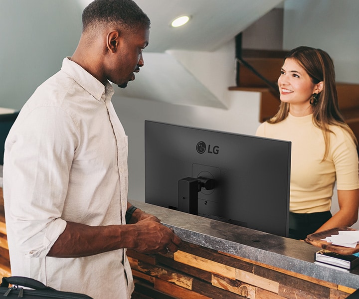 Жінка-адміністратор розмовляє з чоловіком на стійці реєстрації.