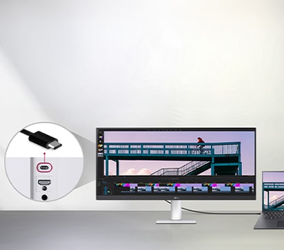 Кабель USB Type-C, підключений між ноутбуком та надширококутним монітором LG, на якому відображається інтерфейс редагування відео, а крупним планом показано порт USB-C на моніторі.	