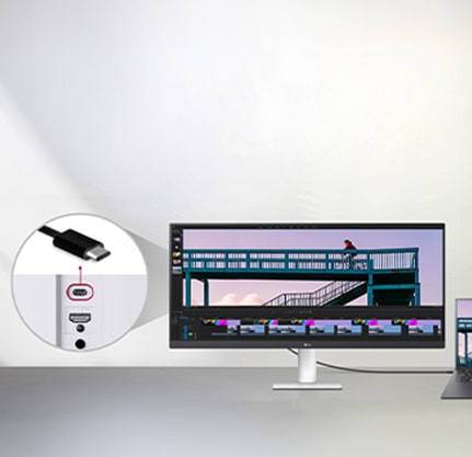 Кабель USB Type-C, підключений між ноутбуком та надширококутним монітором LG, на якому відображається інтерфейс редагування відео, а крупним планом показано порт USB-C на моніторі.	