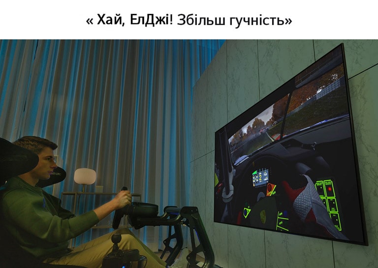 Чоловік в ігровому кріслі, який сидить перед великим телевізором і грає в гонки.