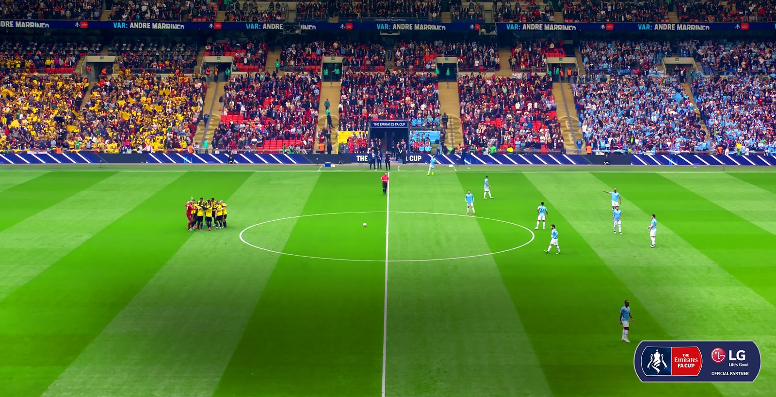 Ширококутний знімок футбольного поля. Гравці збираються в центрі поля, щоб підготуватися до матчу.