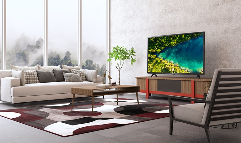 Телевізор у сучасному мінімалістському інтер’єрі, на екрані якого показано вид згори на річку в густому лісі.
