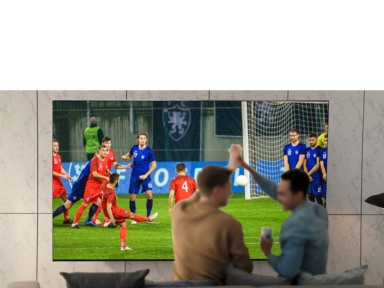 Люди в кімнаті, які дивляться спортивну подію по телевізору з надзвичайно великим екраном