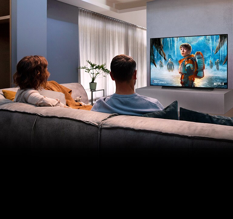 Пара, сидячи на дивані у вітальні, дивиться романтичний фільм по телевізору