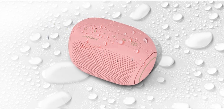 On a white background, LG XBOOM Go is facing up to the left. There are water droplets on and underneath LG XBOOM Go.