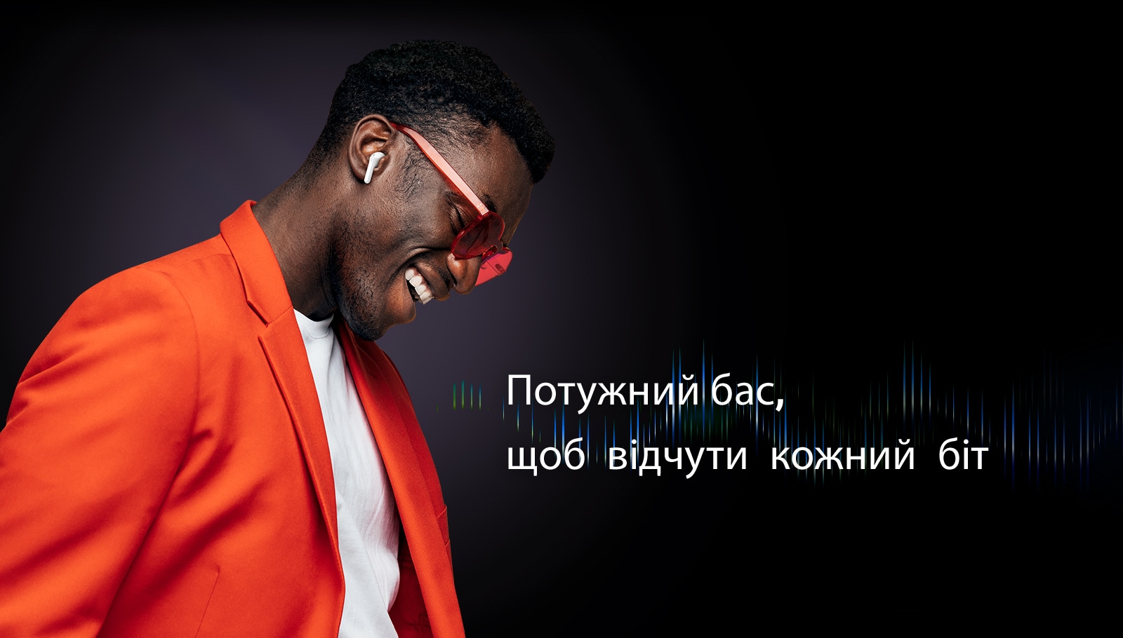 Чоловік у помаранчевому костюмі слухає музику в навушниках TONE Free.