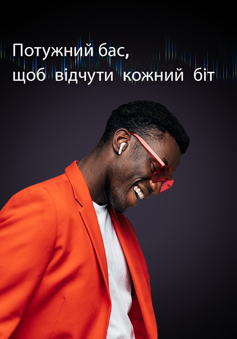 Чоловік у помаранчевому костюмі слухає музику в навушниках TONE Free.