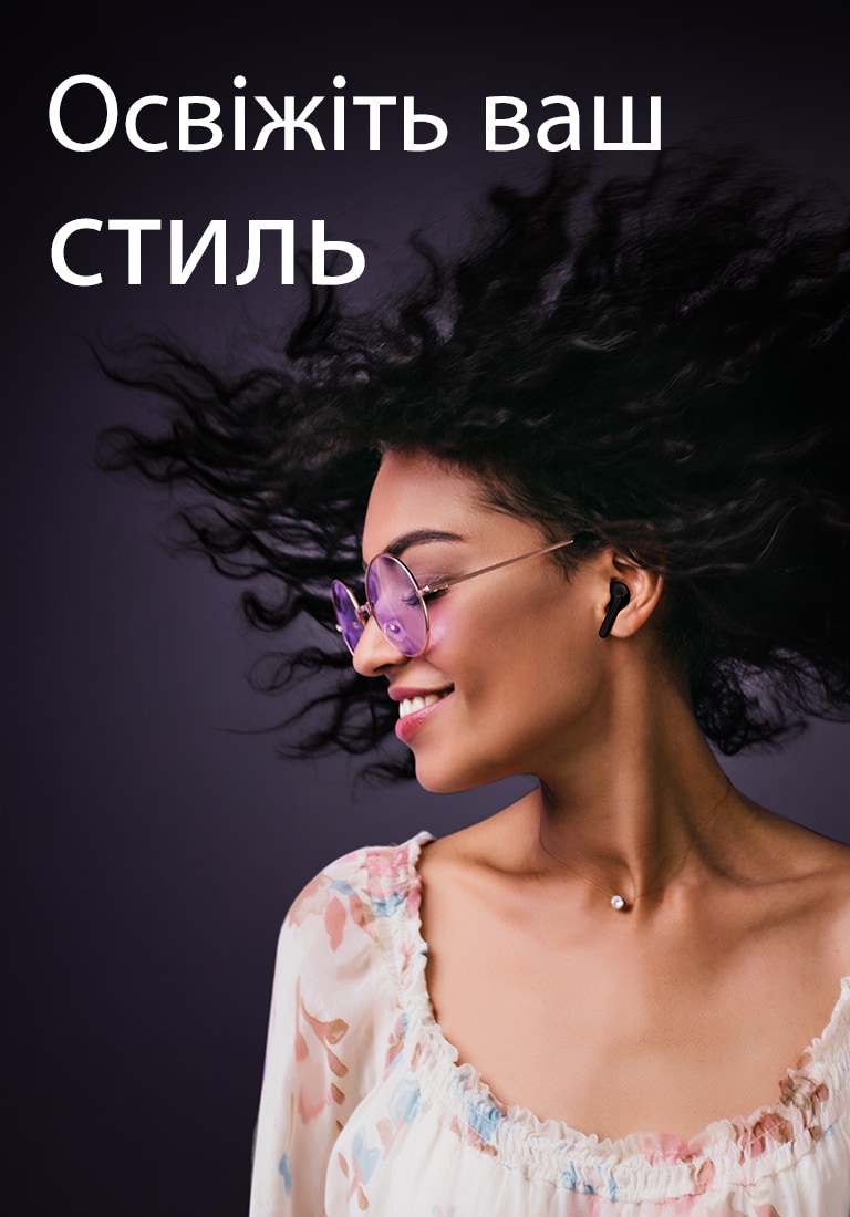 Жінка посміхається, слухаючи музику в навушниках TONE Free.