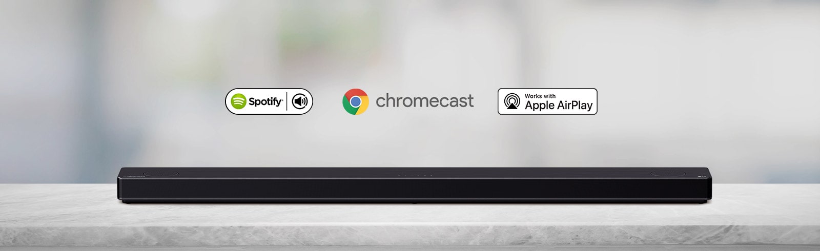Саундбар розташовано на сірій полиці, а також зліва направо показано логотипи платформ штучного інтелекту в такій послідовності: Spotify, Chromecast та  Apple Airplay.