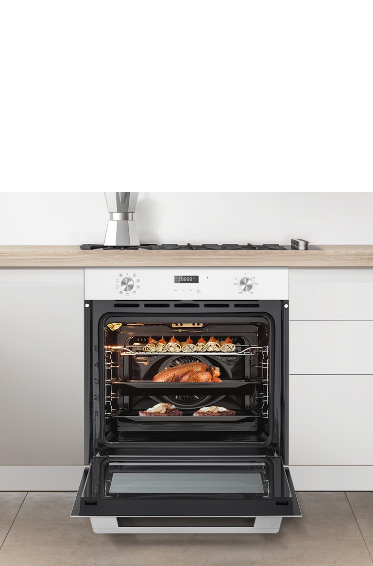 Вбудована духова шафа встановлена на сучасній білій кухні, відкрита і там смажиться курка. 
