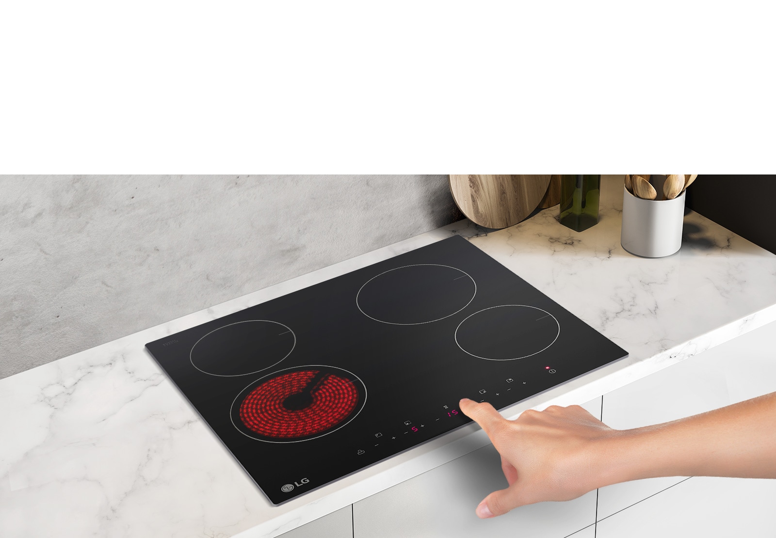 Варильна поверхня знаходиться від кутом, вид зверху вниз. Рука тягнеться до кнопки, щоб натиснути її. Ліва передня конфорка горить червоним.