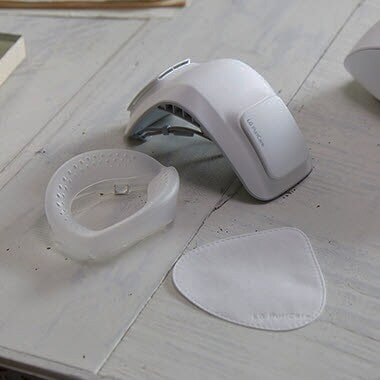 Рука тримає силіконову подушечку, а очисник лежить на столі на фоні.