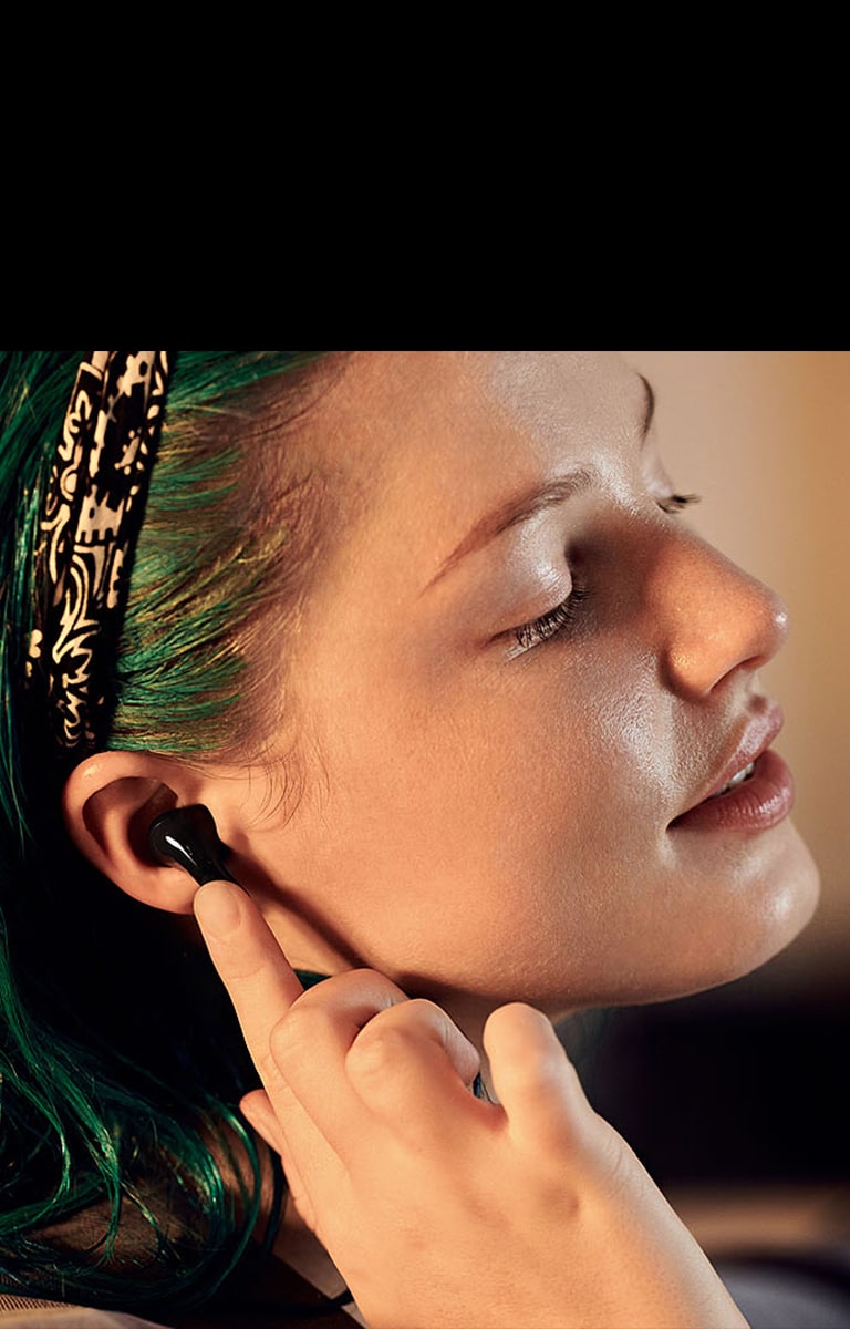 Зображення жінки у профіль. Вона має навушники T90 і торкається одного з них пальцем.