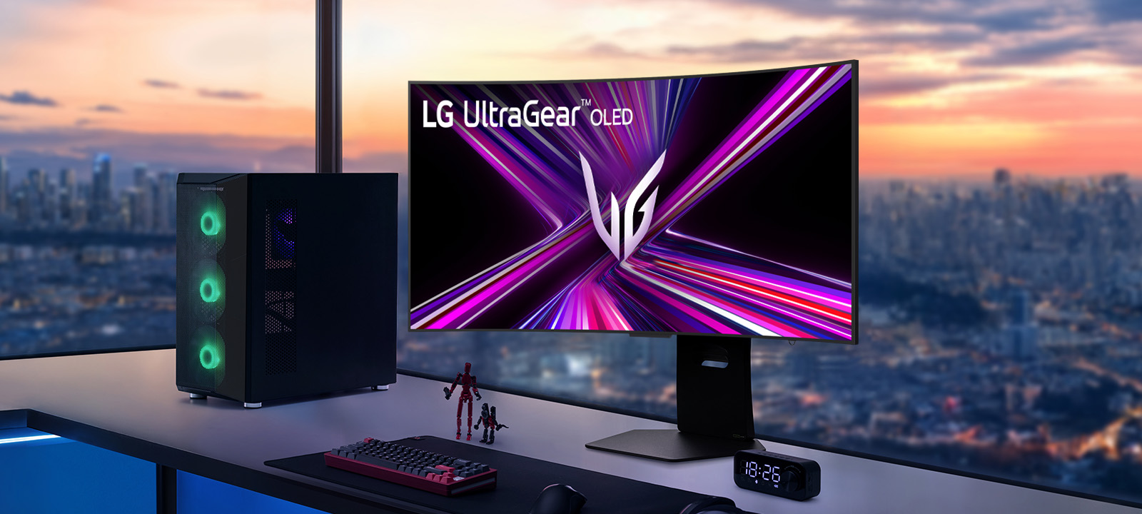 OLED-монітор LG UltraGear на ігровому столі з комп'ютером, з видом на міський пейзаж на заході сонця.
