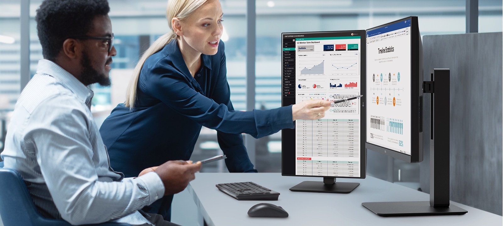 Двоє співробітників чоловічої та жіночої статі обговорюють, дивлячись на монітор в офісі.