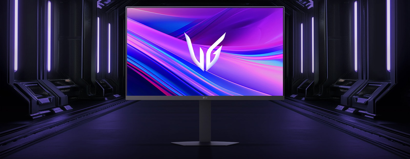 Вигляд спереду ігрового монітора LG UltraGear™ 27G440A на шестикутній підставці, розміщеного у футуристичному коридорі з неоновим підсвічуванням; на екрані — яскраві фіолетово-червоні візерунки з логотипом UltraGear у центрі.
