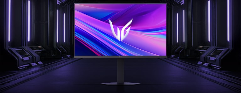 Вигляд спереду ігрового монітора LG UltraGear™ 27G440A на шестикутній підставці, розміщеного у футуристичному коридорі з неоновим підсвічуванням; на екрані — яскраві фіолетово-червоні візерунки з логотипом UltraGear у центрі.