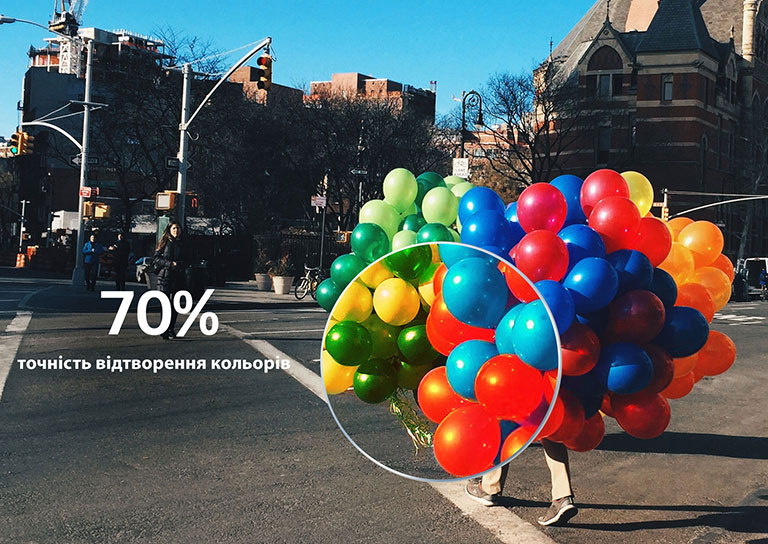 Людина переходить пішохідний перехід, тримаючи в руках кольорові повітряні кульки. Частину кульок збільшено, щоб продемонструвати точність відтворення кольорів (відтворити відео).