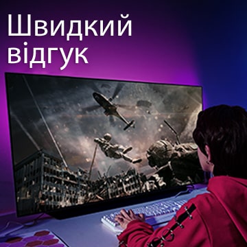 Дівчина грає в комп’ютерну гру на великому екрані телевізора, де зображено солдата, який спускається з гелікоптера.