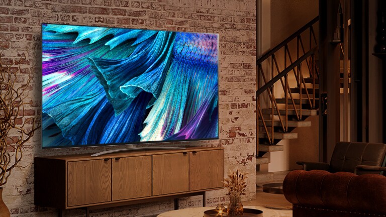 QNED91 установлено на дерев’яній шафі біля цегляної стіни в сучасному інтер’єрі. На екрані крупним планом показано пелюстки у відтінках блакитного.