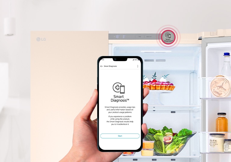На зображенні видно, що дверцята холодильника залишили відкритими. На  передньому плані зображено руку, що тримає смартфон, на якому видно інтерфейс програми Smart Diagnosis.